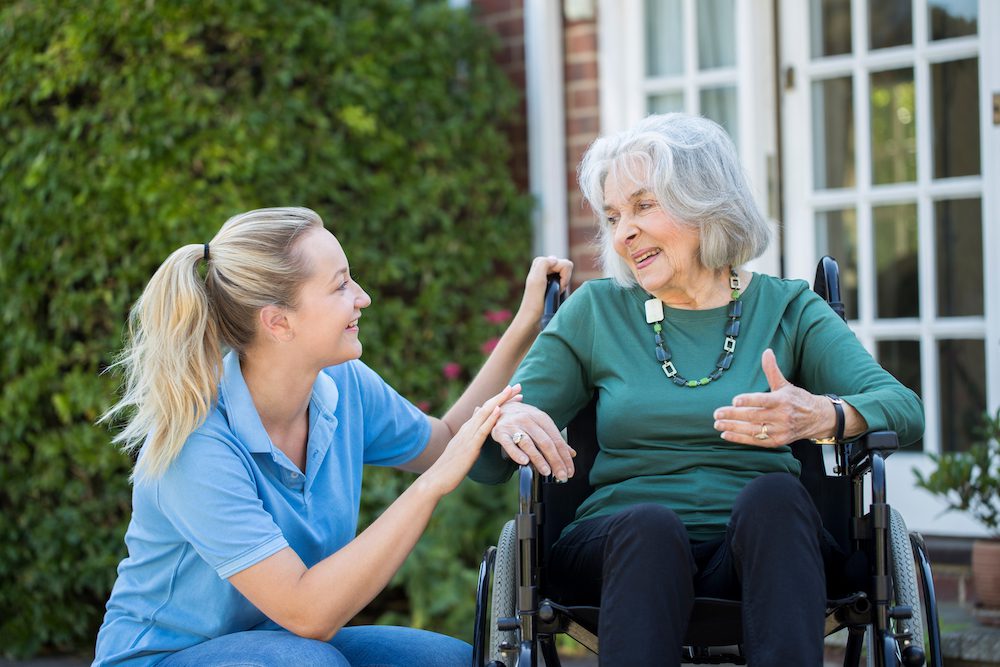 elderly woman in wheelchair with caregiver